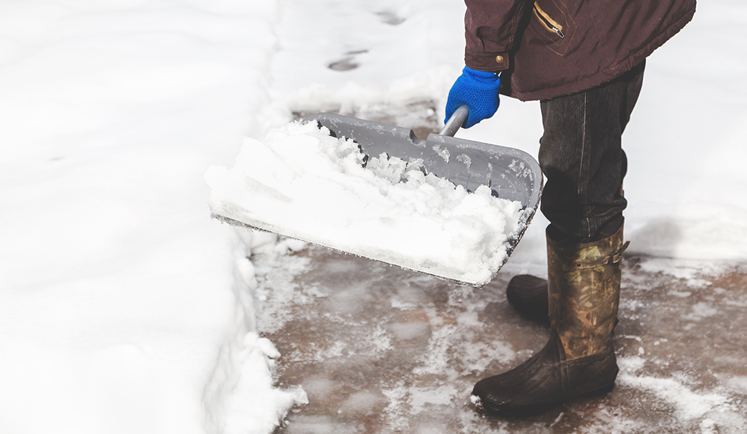cleaning the yard of snow. A man in a jacket and boots, holding a plastic shovel with snow